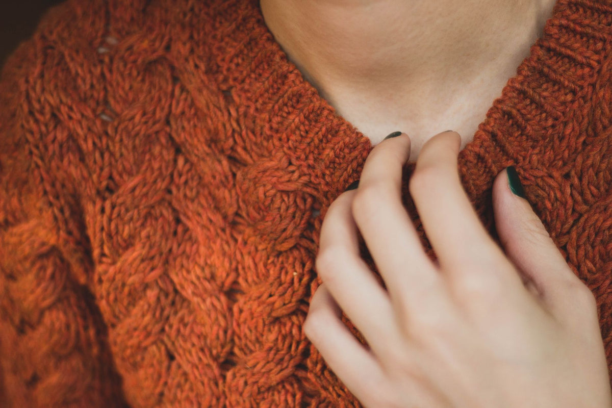 Comment laver un pull en cachemire : gros plan sur une maille douce portée, main posée au niveau du col