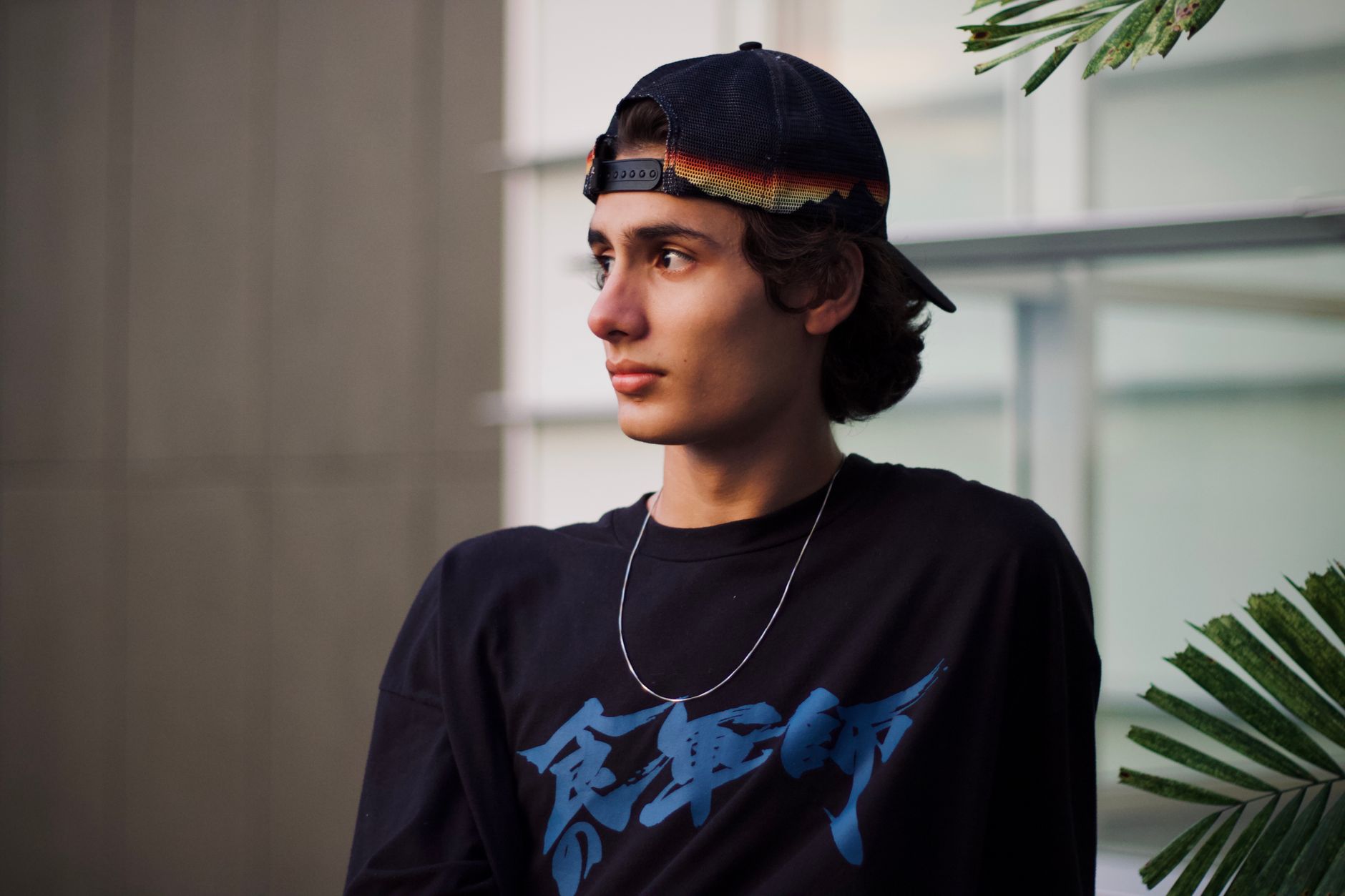 Jeune homme portant une casquette noire à l'envers en tenue streetwear urbaine
