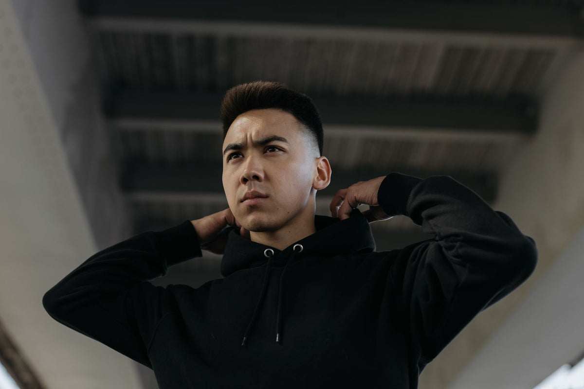 Jeune homme en sweat à capuche noir sous un pont urbain, illustration de la streetwear definition