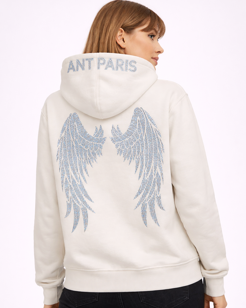 Sweat à capuche off-white ATNT Paris porté par mannequin femme mince, vue dos trois-quarts, ailes d’ange en strass argent, photo studio fond blanc