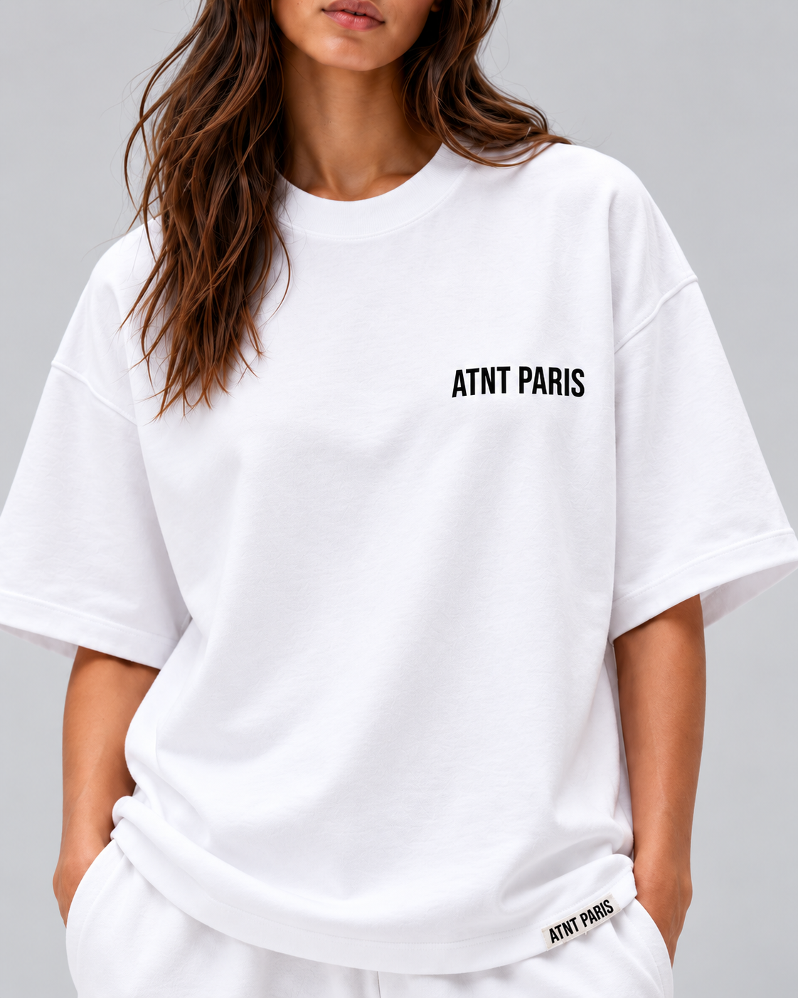 T-shirt oversize blanc Essentials ATNT PARIS — détail du logo poitrine, de la coupe et de l'étiquette