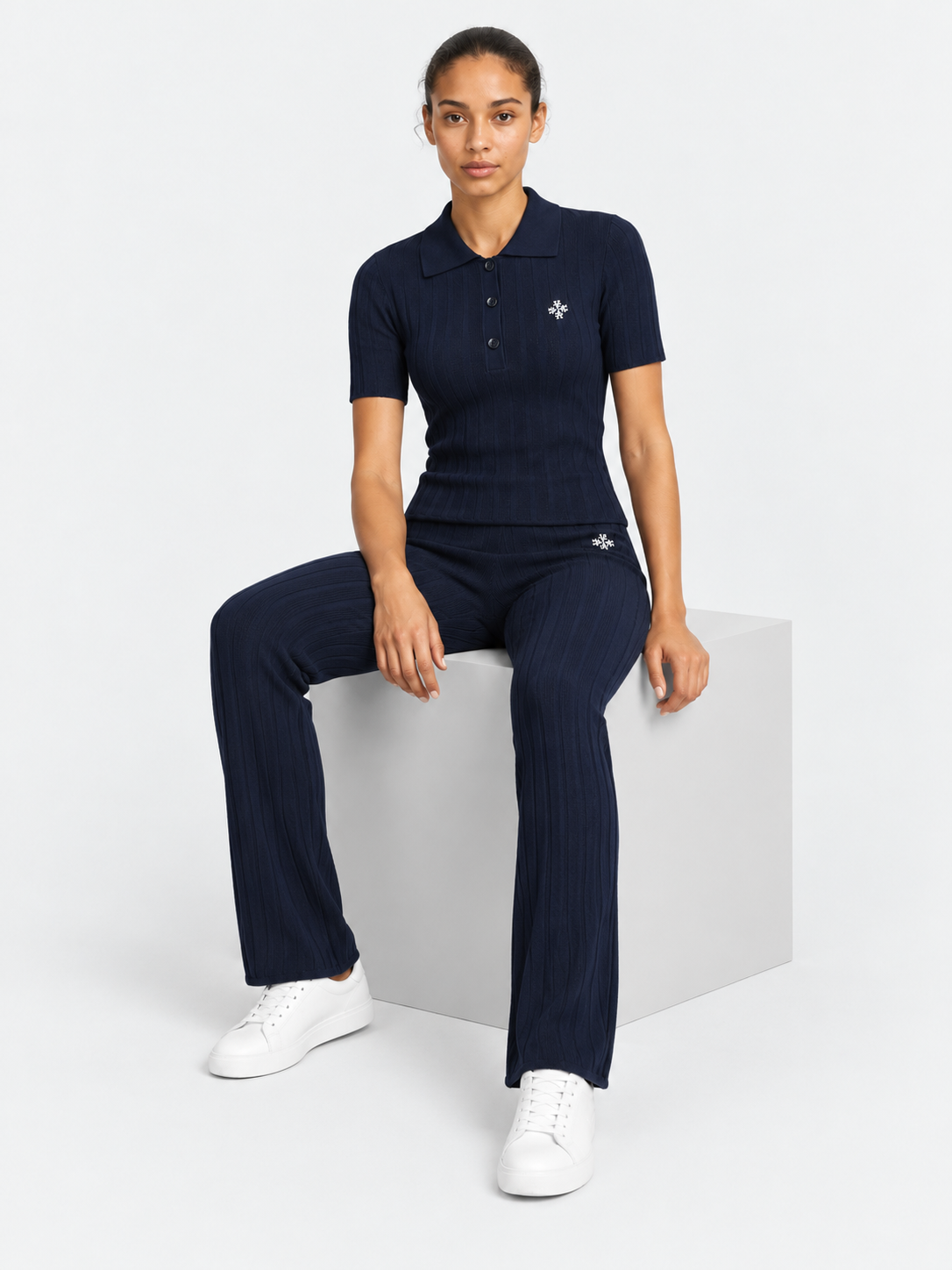 ATNT Tracksuits studio : Pantalon riviera Atnt Signature en maille côtelée Navy, vue assise sur fond gris clair
