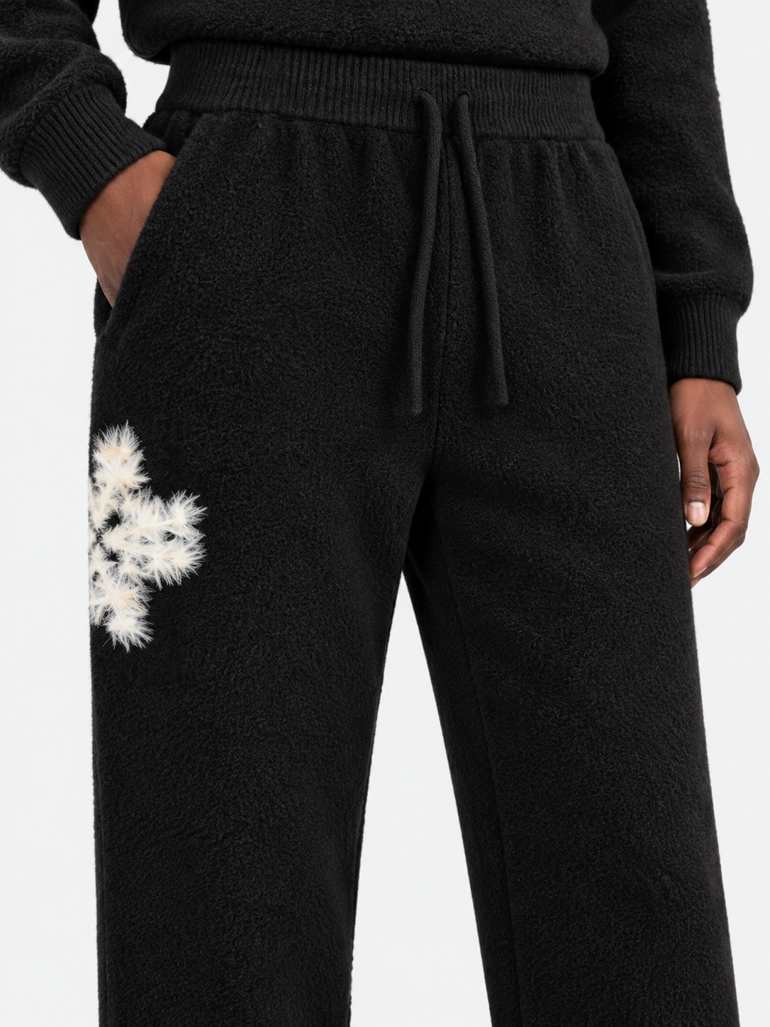 ATNT Tracksuits studio : Pantalon de jogging en maille fluffy monogramme signature noir, détail de la matière sur fond gris clair