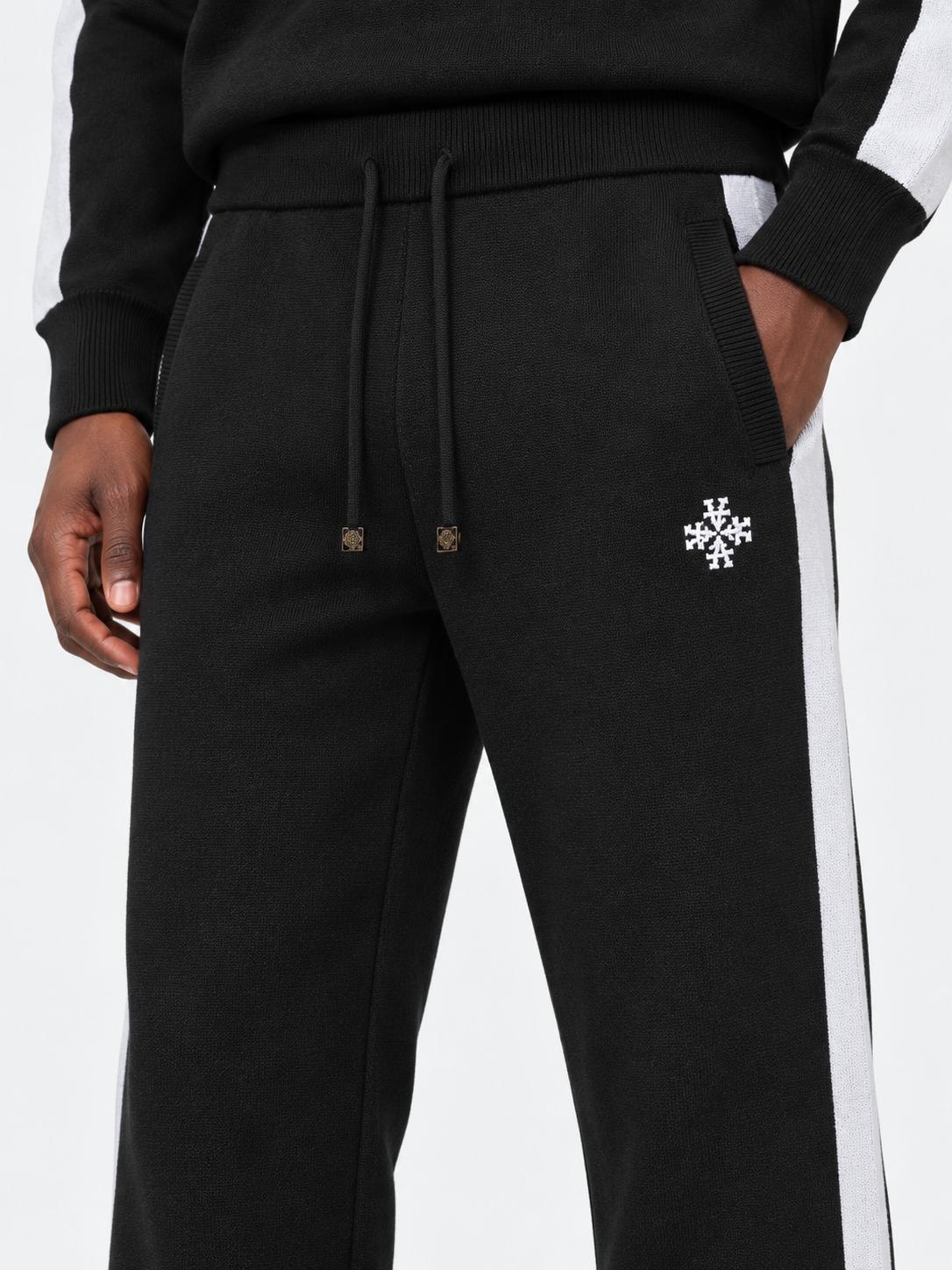 ATNT Tracksuits studio : Pantalon Knitted Noir Signature rayures latérales, détail de la matière sur fond gris clair