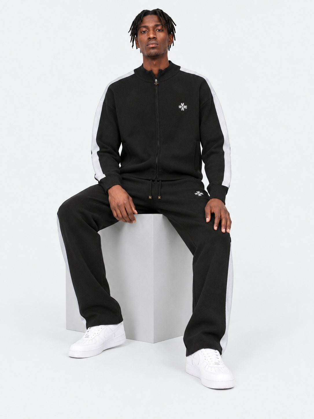 ATNT Tracksuits studio : Pantalon Knitted Noir Signature rayures latérales, vue assise sur fond gris clair
