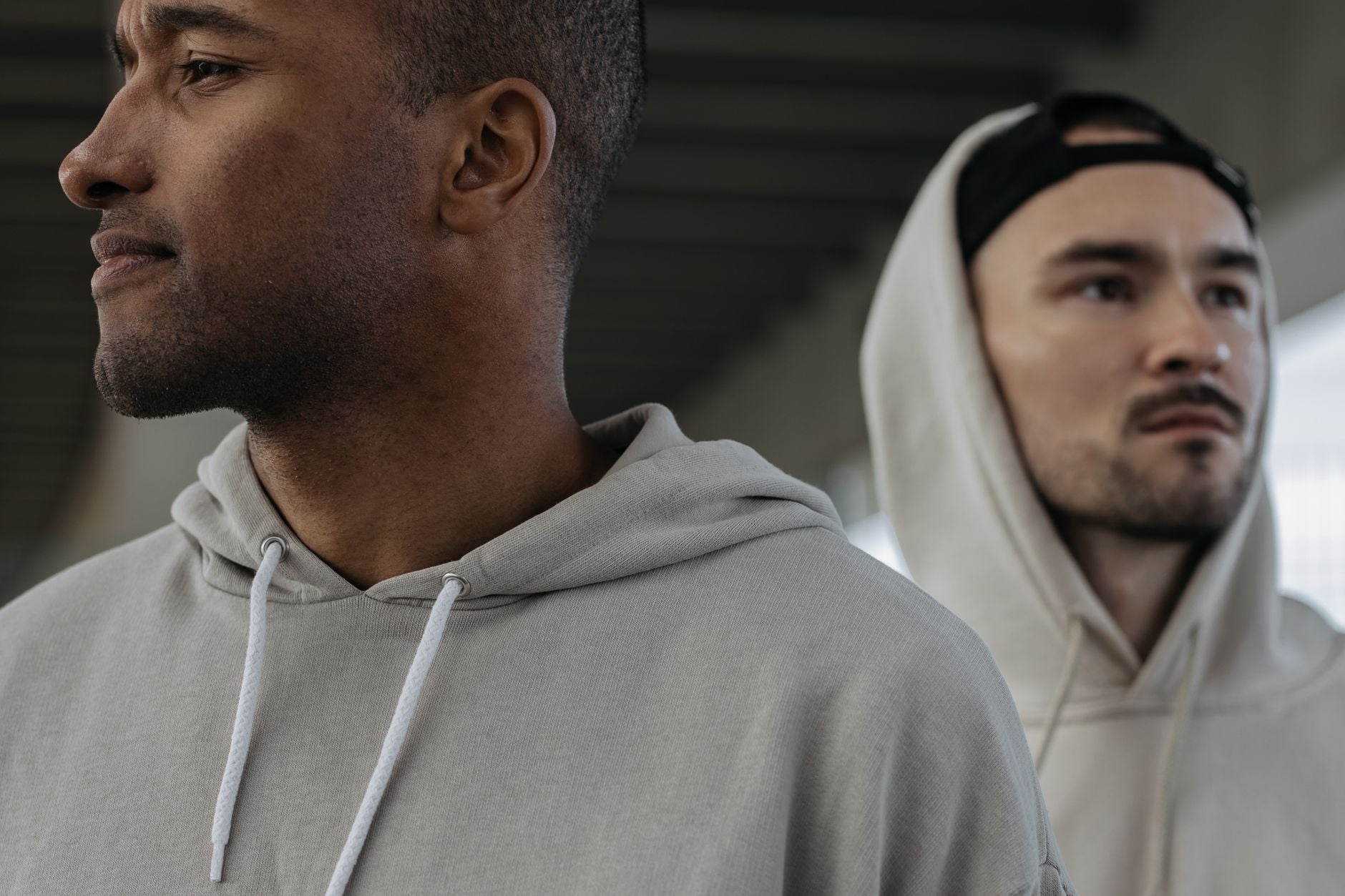 Deux hommes portant des sweats à capuche unis en contexte urbain streetwear