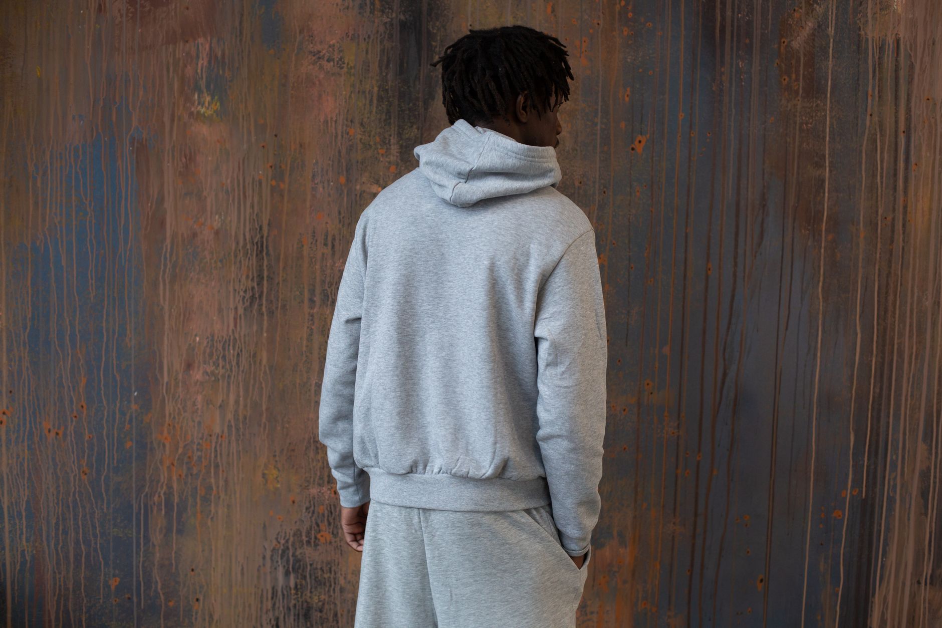 Homme en jogging gris coordonné vu de dos dans une ambiance urbaine industrielle