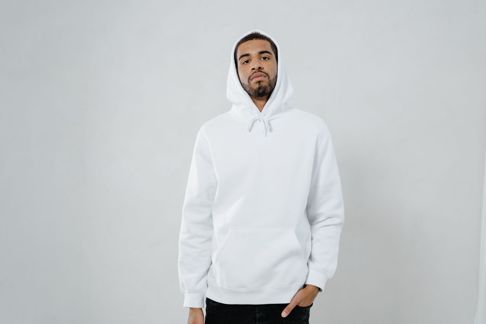 Homme en sweat blanc à capuche uni posant avec style streetwear urbain