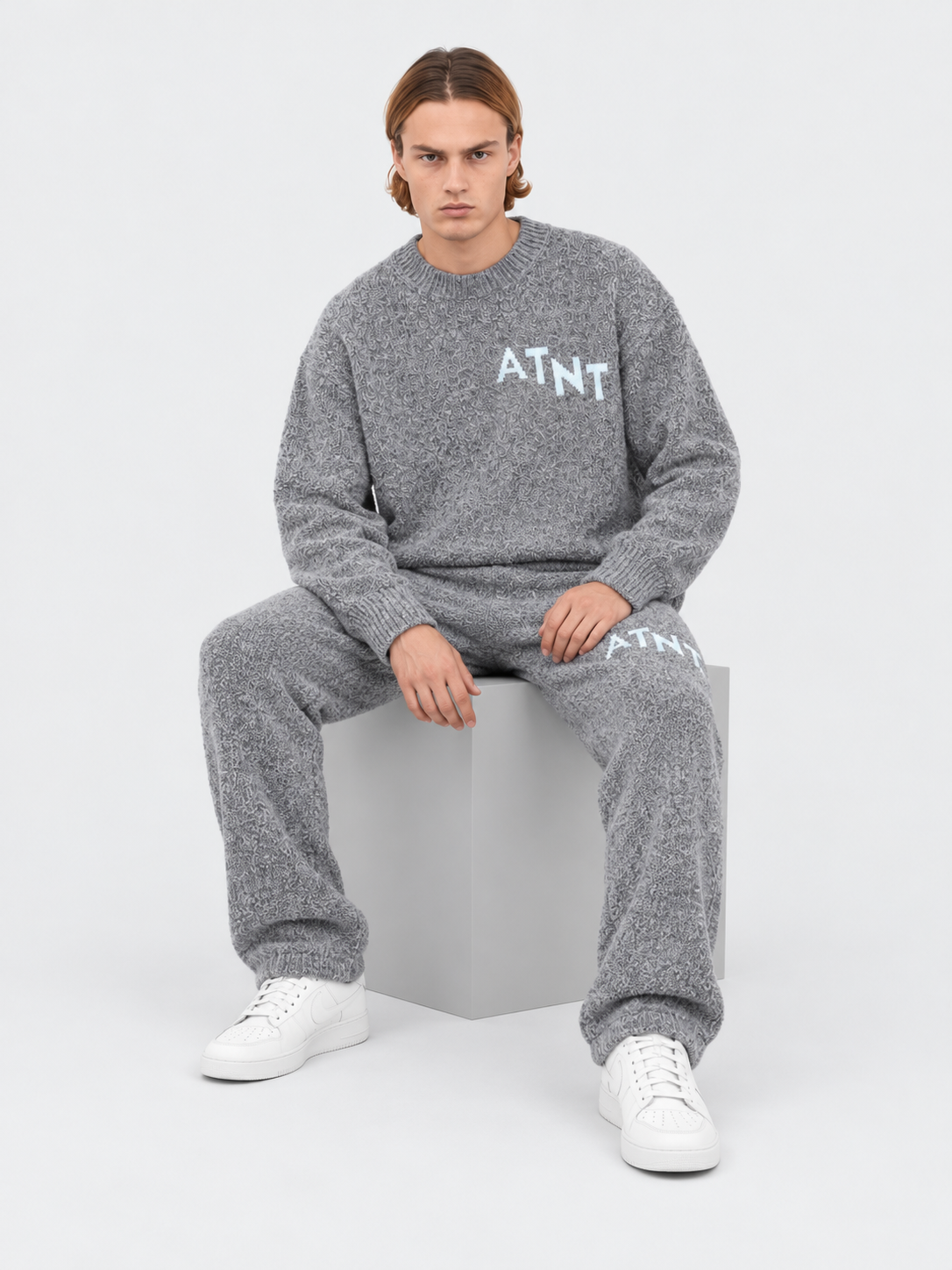 ATNT Tracksuits studio : Jogging Oversize Gris Effet Cachemire, vue assise sur fond gris clair