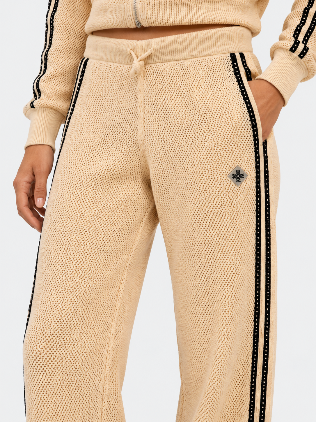 ATNT Tracksuits studio : Pantalon de Survêtement Signature Beige  – Détail Crochet, détail de la matière sur fond gris clair