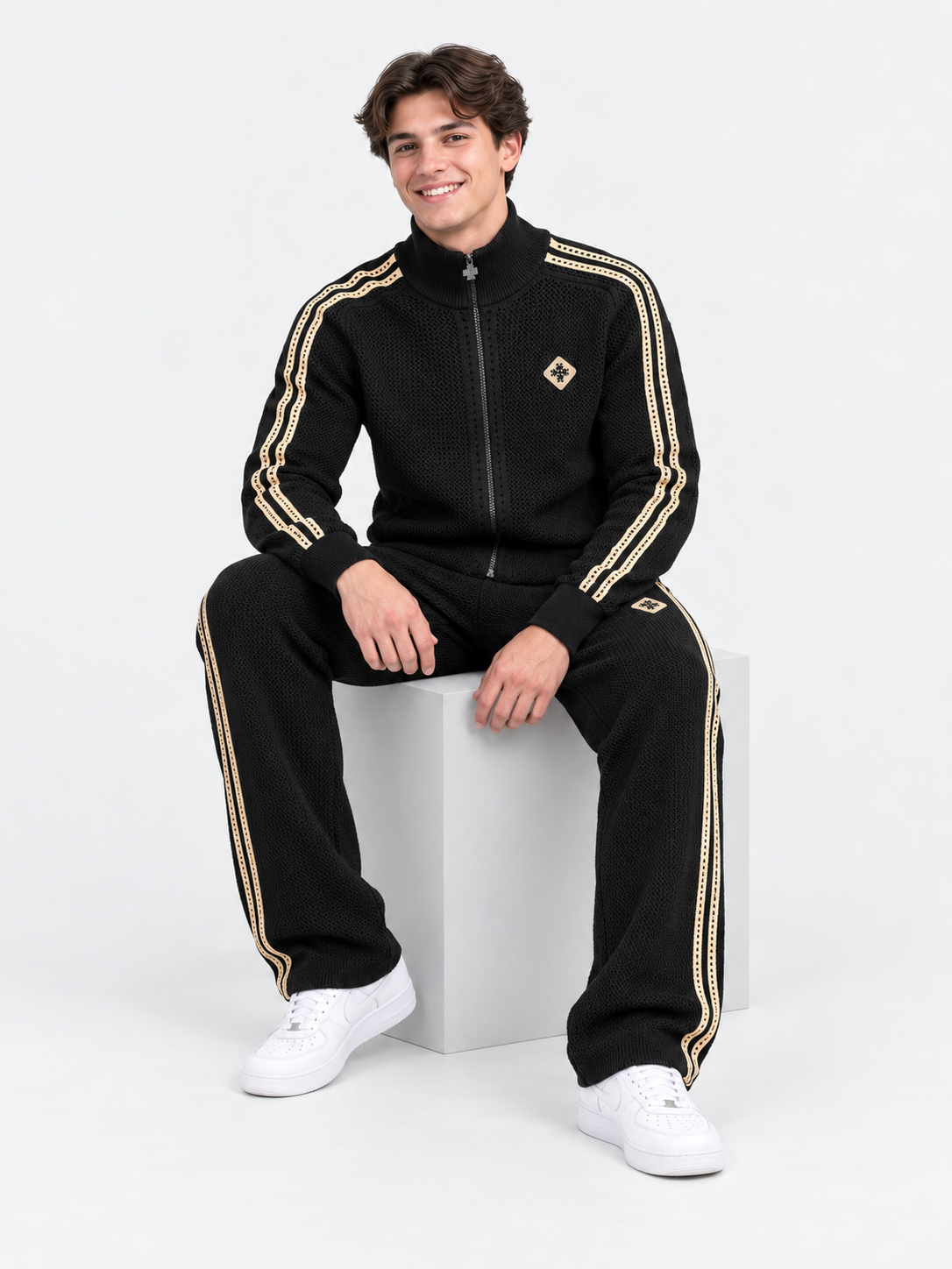 ATNT Tracksuits studio : Ensemble de Survêtement Signature Noir - Crochet, vue assise sur fond gris clair