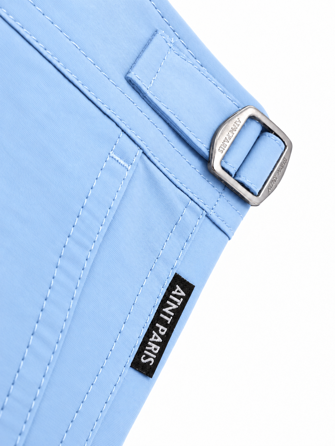 Short de bain riviera bleu ciel ATNT PARIS, détail de la patte de réglage et de l’étiquette.